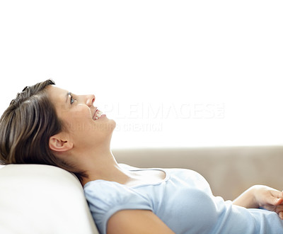 Smiling female lying relaxed on couch and looking upwards