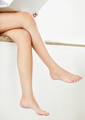 Image of that woman\'s legs who is using a laptop on the counter