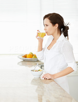 Young woman drinking juice at kitchen counter