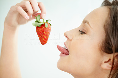 Closeup profile image of a female about to lick it a strawberry