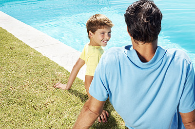 Mature man and his little son sitting at swimming pool