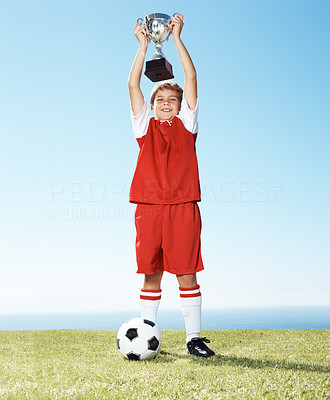 Happy little football champ holding up a winners trophy