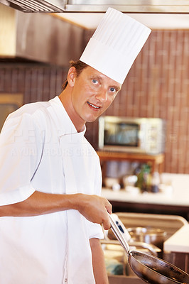 Happy young cook cooking in restaurant