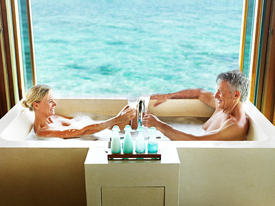 Romantic mature couple in bubble bath with champagne