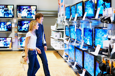 Young couple in electronics store looking at TVs