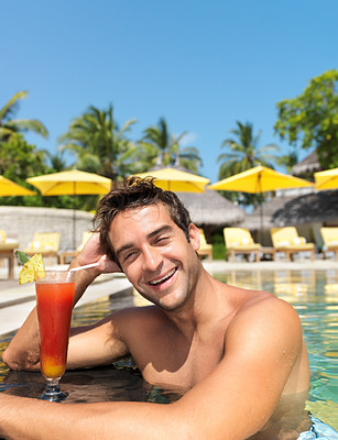 Happy young guy in the pool with a cocktail