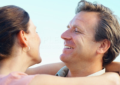 Smiling mature couple looking at each other with arms around