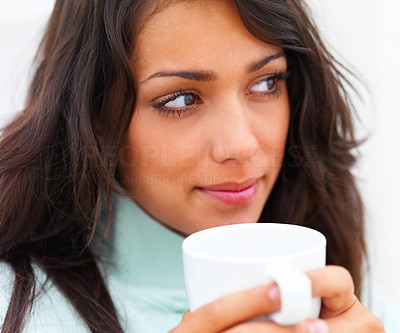 Closeup of a beautiful young lady holding coffee cup and looking away