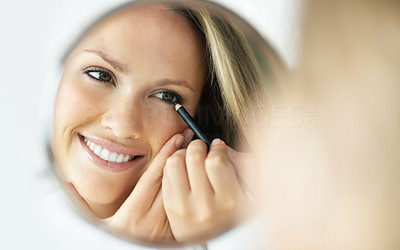 Smiling woman with an eye liner looking at mirror