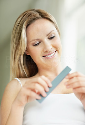 Smiling young blond female filing her nails