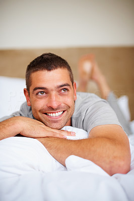 Young guy lying on bed and looking away