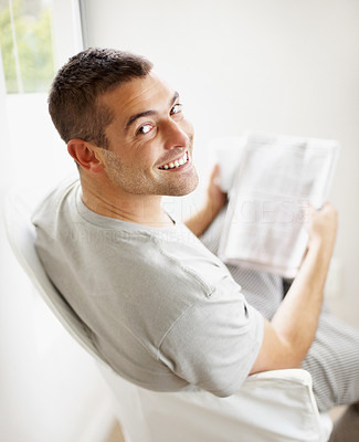 Happy young guy reading newspaper