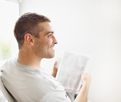 Smart young guy with newspaper looking away