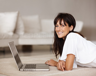 Happy young female lying on the floor using a laptop