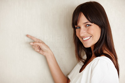 Lovely young female pointing at the empty wall