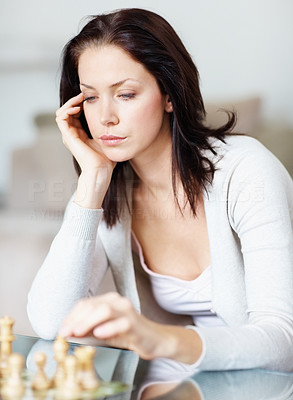 Depressed young female playing a game of chess on her own