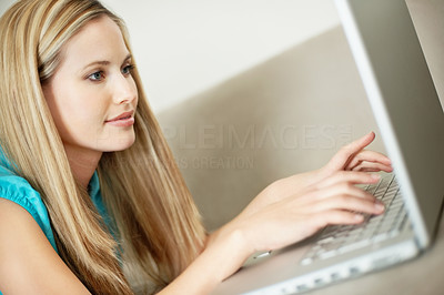 Side view of a young woman working on a laptop on couch