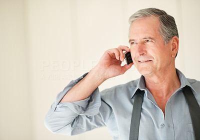 An elderly business man talking on cell phone with copyspace