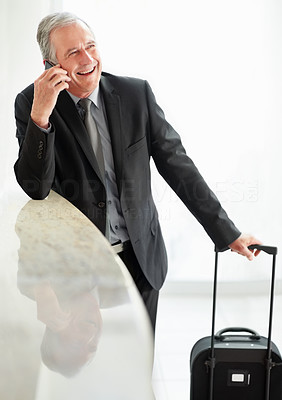 Happy man with his luggage and talking over the cell phone