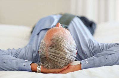 Senior business man lying in bed with hands behind head