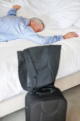 Exhausted matured man lying in bed at hotel