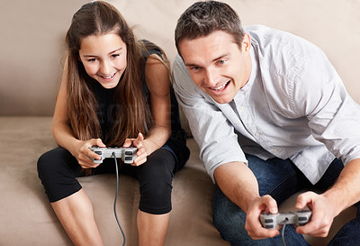 Cheerful little girl with her father playing video games at home