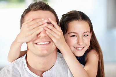 Playful little girl covering her father\'s eyes from behind