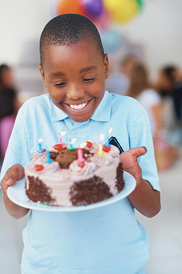 Excited young boy holding his birthday cake