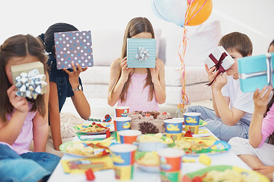 Young kids covering their faces with gifts at a birthday party