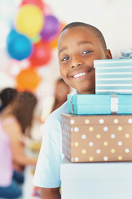 Happy little boy with pile of gifts at a birthday party