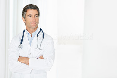 Middle aged doctor with arms folded looking at copy space