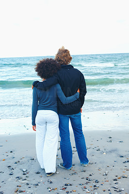 Couple standing on beach, facing the sea