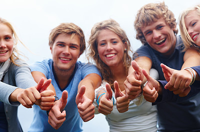Young teenage boys and girls showing thumbs up sign in a line