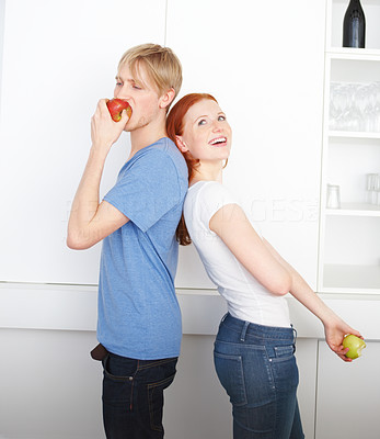 Man and woman standing back to back and eating apple