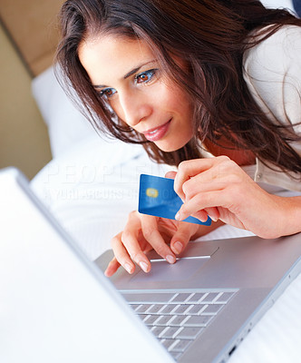 Closeup portrait of a beautiful woman lying on bed with credit card in her hand