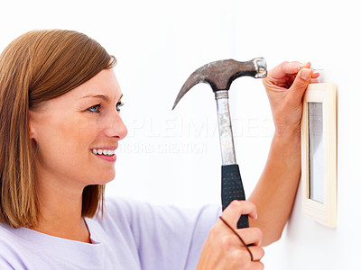 Closeup of a happy woman using hammer on the wall