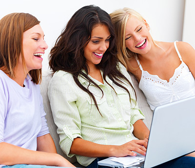 Three happy young female friends using laptop
