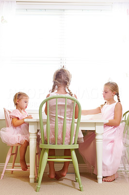 Three smiling girls having tea at dining table