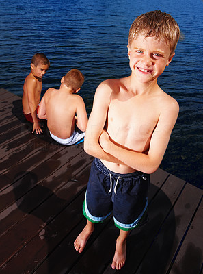Small boy standing on a deck with friends sitting in background