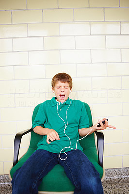 Portrait of young boy listening to music sitting on chair