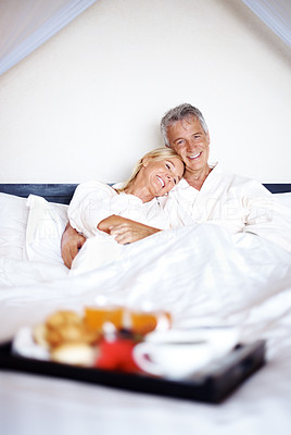 Happy mature couple on bed with breakfast