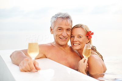 Romantic middle aged couple in a pool with drinks