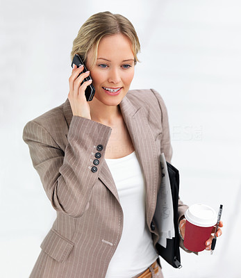 Young beautiful smiling business woman talking on her cell phone and drinking coffee
