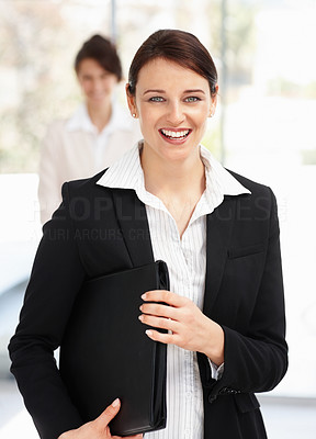 Business woman holding folder while a colleague in background