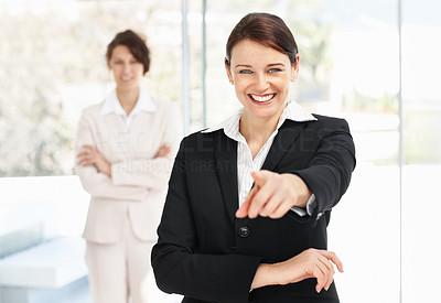 Young business woman pointing at you and her colleague in blur