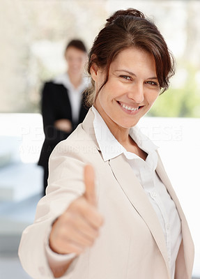 Business woman with colleague in blur showing you a thumbs up