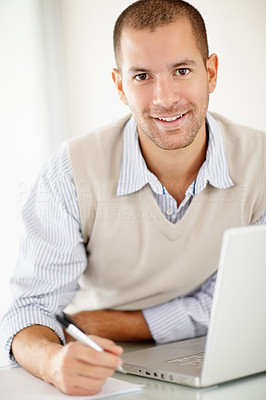 Smiling middle aged man referring something on paper from laptop