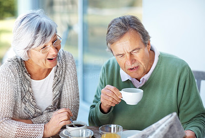 Old couple reading newspaper and having breakfast
