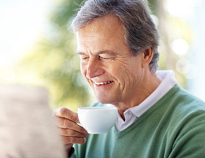 Happy senior male reading a newspaper in morning