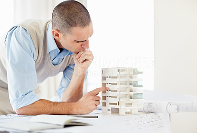 Busy middle aged architect working on a building model at office